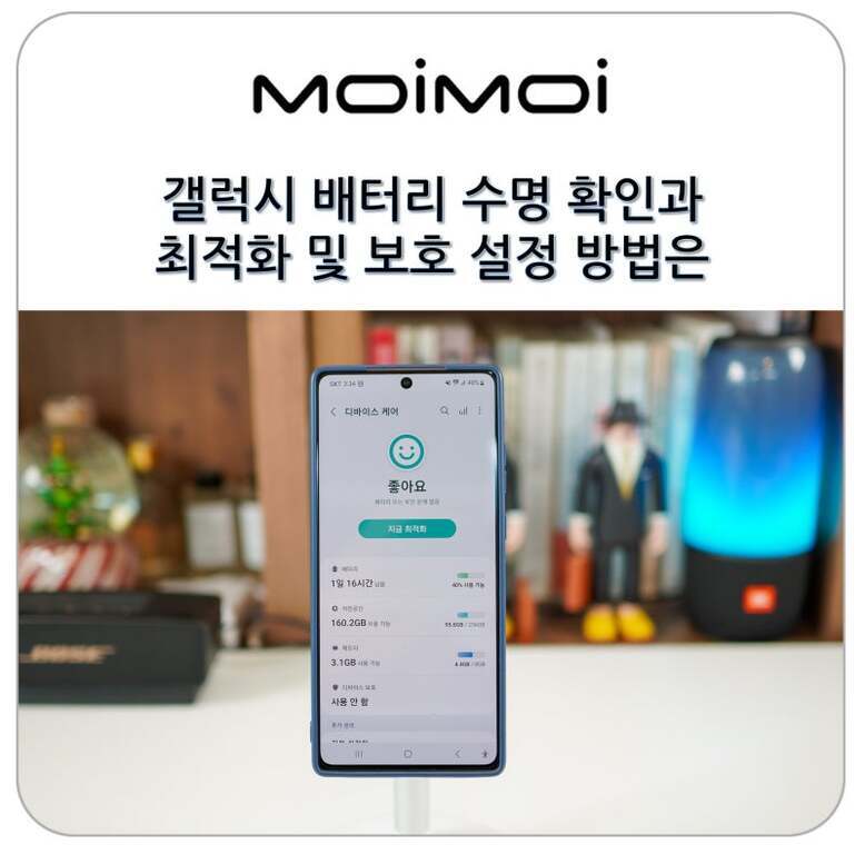 MOIMOI 로고와 함께 '갤럭시 배터리 수명 확인과 최적화 및 보호 설정 방법은'이라는 문구가 상단에 있고, 하단에는 갤럭시 스마트폰이 디바이스 케어 앱 화면을 보여주는 이미지