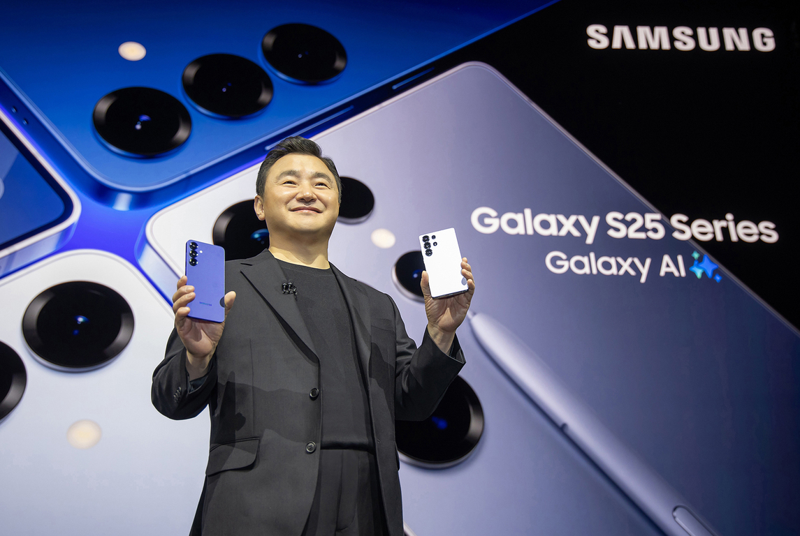 한 남성이 삼성 갤럭시 S25 시리즈 스마트폰 두 대를 들고 무대에 서 있으며, 배경에는 'Galaxy S25 Series Galaxy AI'와 삼성 로고가 보인다.