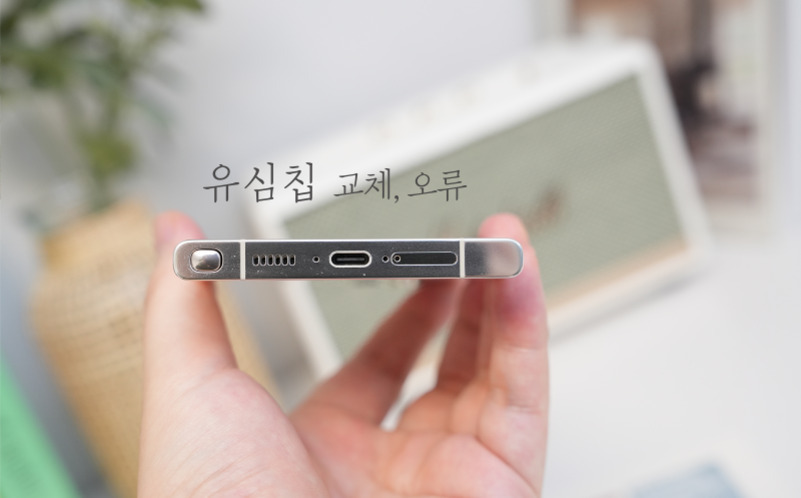한 손에 스마트폰을 들고 하단부를 보여주는 사진. 상단에는 '유심칩 교체, 오류'라는 문구가 적혀 있다.