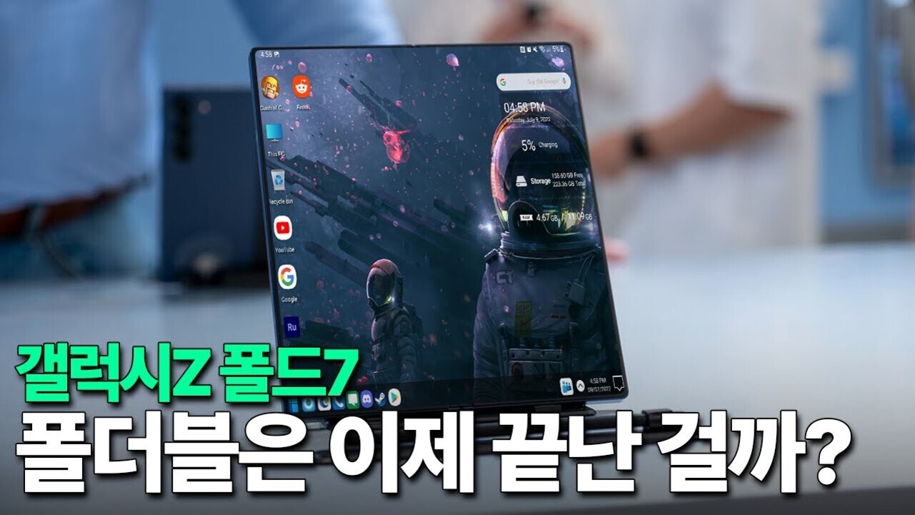 책상 위에 펼쳐진 갤럭시 Z 폴드7 스마트폰이 보이고, 화면에는 우주인 배경화면과 여러 앱 아이콘이 있다. 하단에는 '갤럭시Z 폴드7 폴더블은 이제 끝난 걸까?'라는 한국어 문구가 적혀 있다.