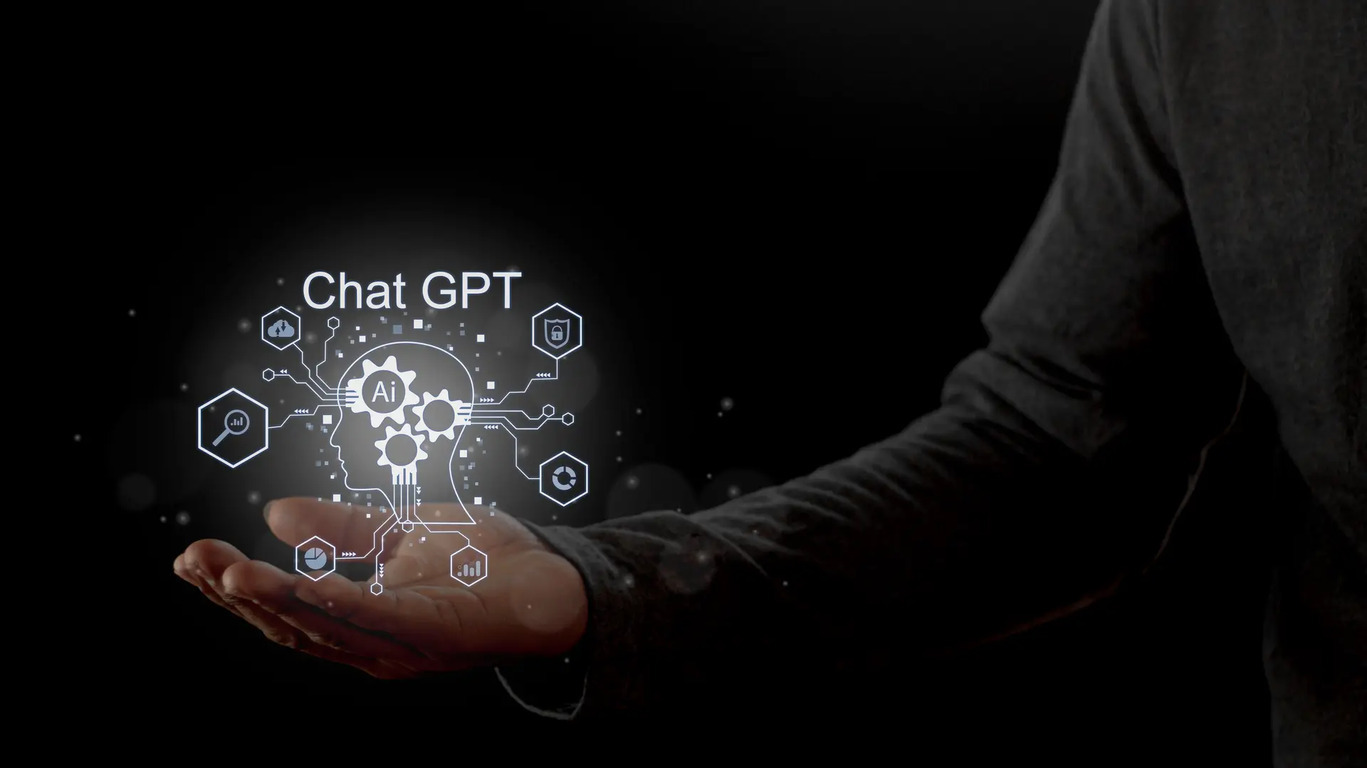 AI 보안 및 데이터 보호: 모바일 환경과 기업용 챗봇의 실전 대응 가이드 2 검은 배경 위에 한 사람이 손바닥을 펼치고 있으며, 손 위에는 'Chat GPT'와 인공지능(AI) 관련 아이콘이 있는 디지털 머리 이미지가 떠 있다.
